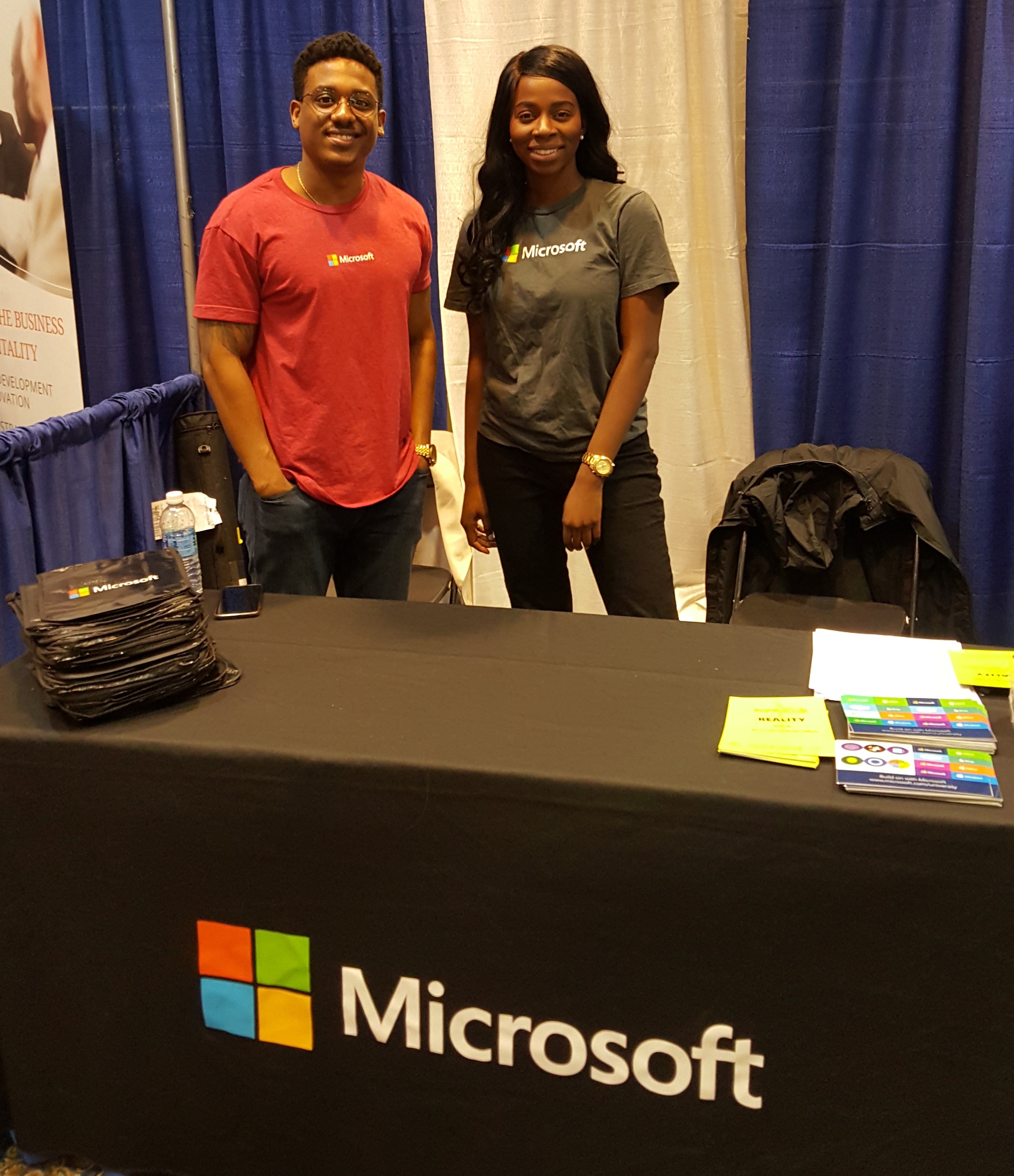 Two members of the Diversity and Inclusion recruiting team at a Microsoft-branded table during a university recruiting event.
