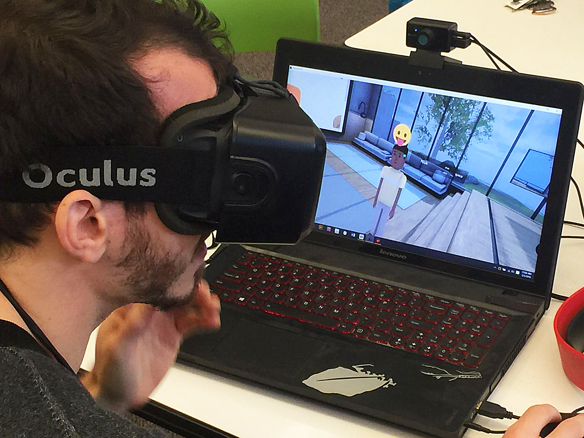 A user wearing an Oculus headset while testing the conVRse prototype on a laptop, with the AltSpaceVR café visible on screen.